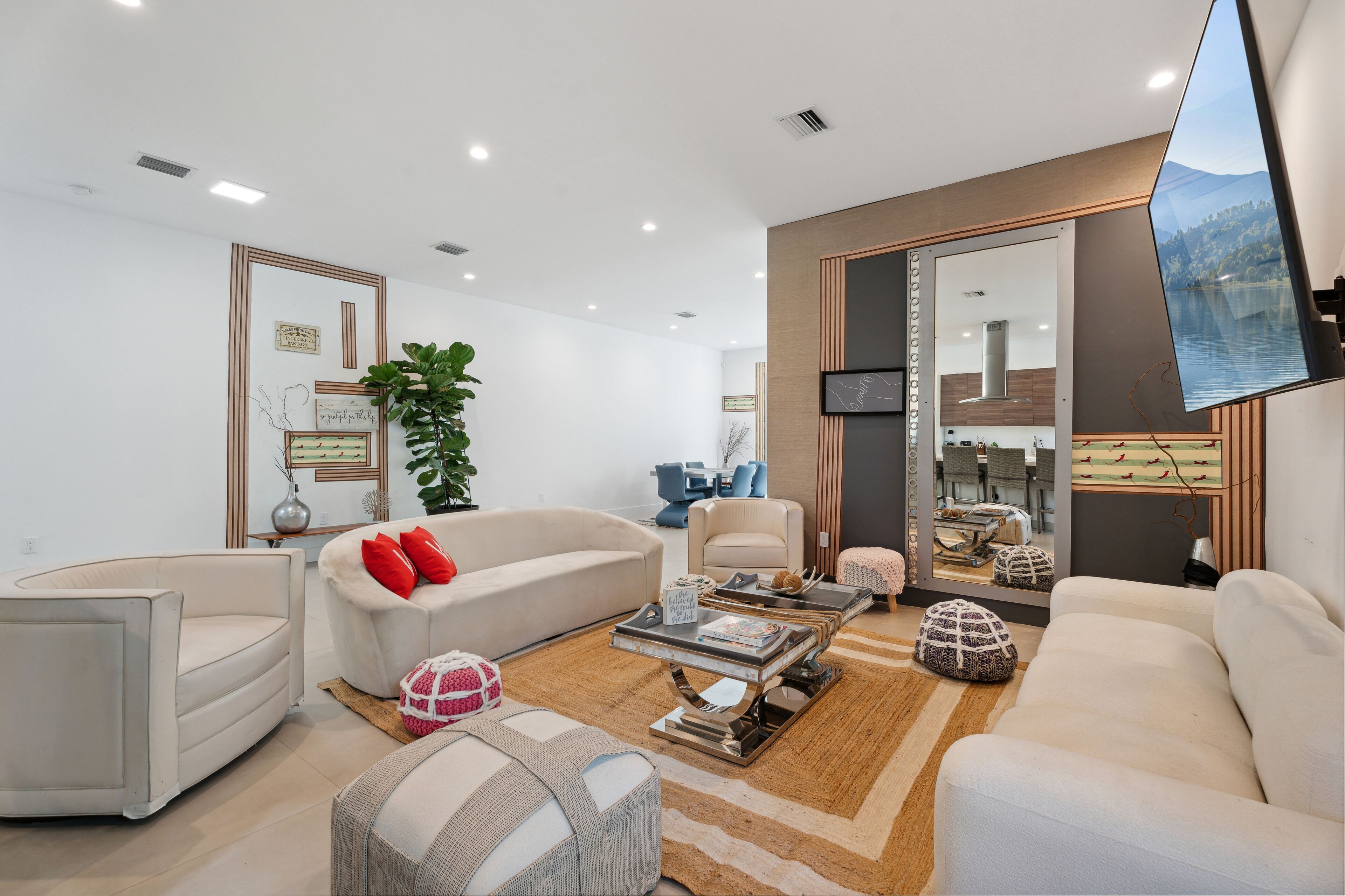 A modern living room with a sofa, armchairs, a coffee table, and a TV mounted on a wall.