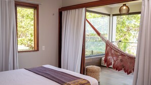 Un dormitorio con cama, vistas al exterior y una hamaca.