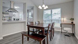 Une cuisine moderne avec un coin repas, une grande fenêtre et un luminaire suspendu.