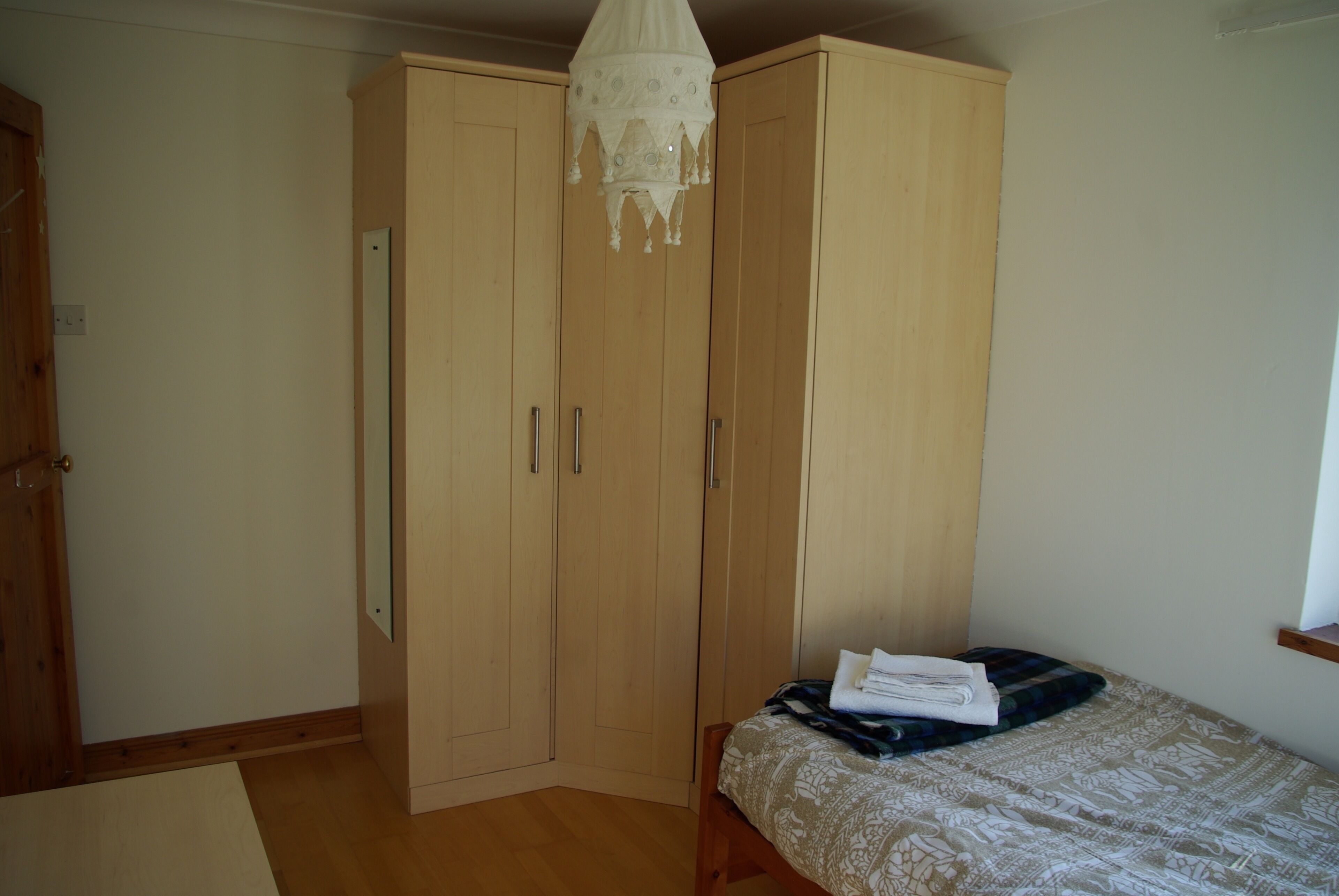 A bedroom with a bed, a wardrobe, and a hanging light fixture.