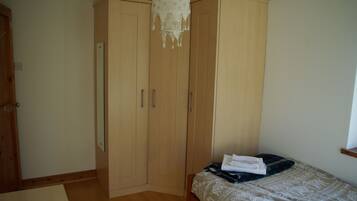 A bedroom with a bed, a wardrobe, and a hanging light fixture.