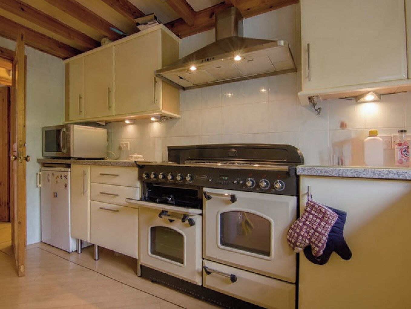 Cuina amb armaris blancs, microones, fogó i forn.