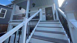 A two-story house with a white exterior, a front porch with a staircase, and a black metal gate. - Big Deck Energy-1 block to Beach & Boardwalk (Atlantic City)