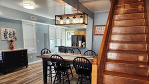 A dining area with a wooden table and chairs, a staircase, and a kitchen in the background. - Big Deck Energy-1 block to Beach & Boardwalk (Atlantic City)