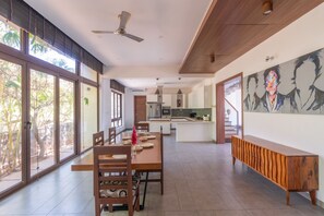Un comedor amplio con una mesa de madera larga y sillas, un banco a lo largo de la pared, y ventanas grandes que ofrecen vistas al exterior.
