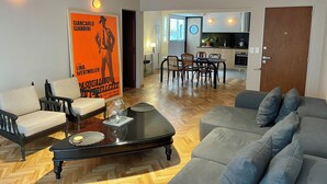 Un salon moderne comprenant un canapé, des fauteuils, une table basse et un coin repas avec des chaises et une table.