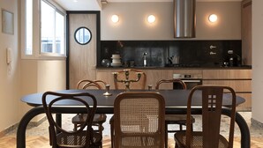 Une cuisine moderne avec un coin repas, comprenant une table ronde, des chaises en bois et un plan de travail noir.