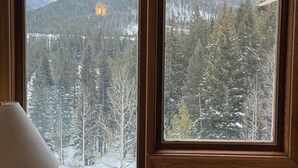 A room with a large window offering a view of a snowy forest and mountains. - Pool Hot Tub Free Garage · Remodeled Studio (Winter Park)