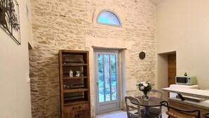 Una stanza accogliente con una parete in pietra, una libreria in legno, un tavolo da pranzo con sedie e un piccolo angolo bar.