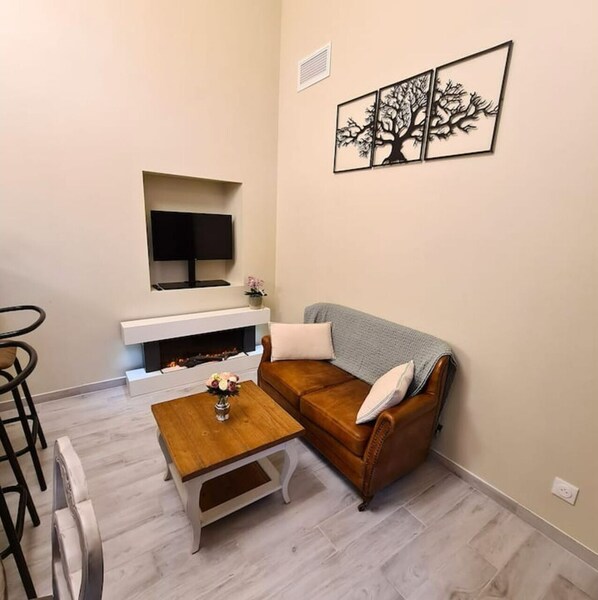Un salon comprenant un canapé, une table basse, un téléviseur fixé au mur et une cheminée.