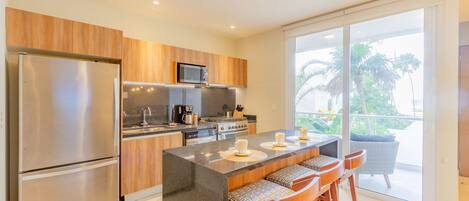 Una cocina moderna con una isla central, electrodomésticos de acero inoxidable y vistas a un balcón.
