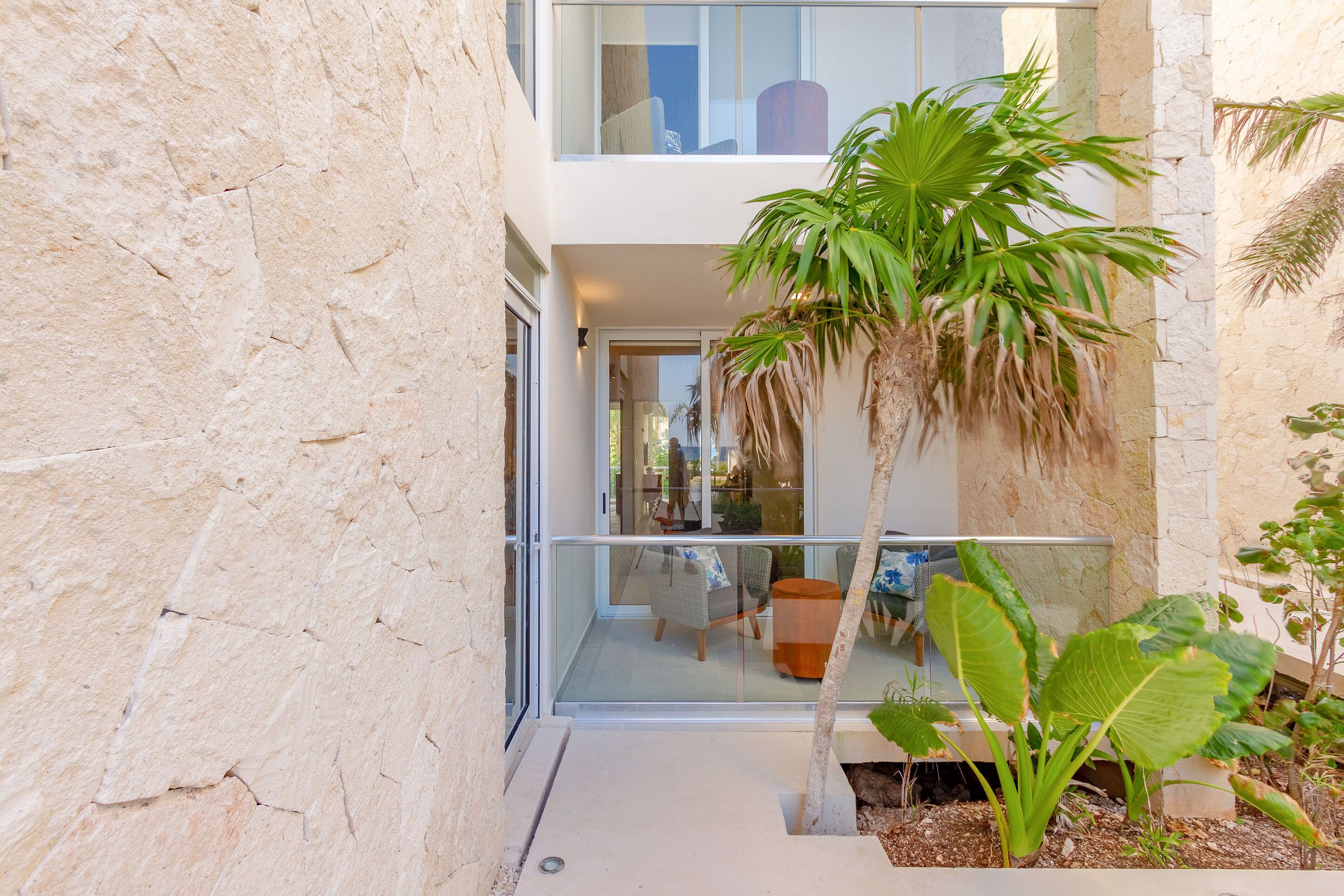 Een modern gebouw met een glazen balkon, een palmboom en een klein terras.