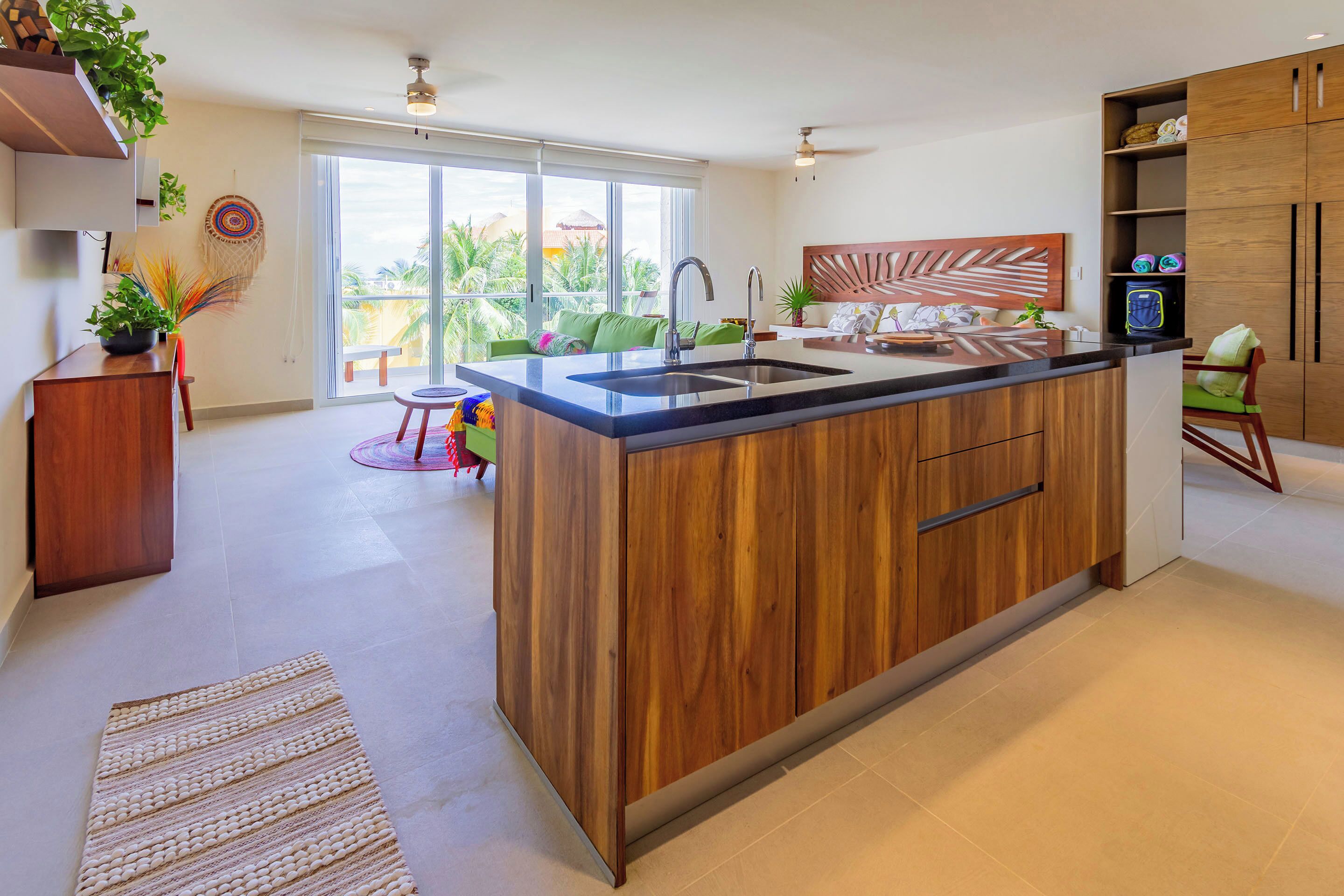 Cocina moderna con una isla central, armarios de madera y un amplio ventanal con vistas al exterior.