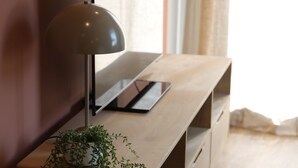 A wooden console table with a modern lamp, a flat-screen TV, and a potted plant. - Maison Décorée Avec Charme, Parfaitement Équipée Pour 6 Personne, Proche Plage (Barneville-Carteret)