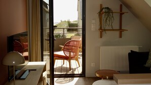 A modern room with a sliding glass door leading to an outdoor area, a desk with a lamp, a chair, and a small table. - Maison Décorée Avec Charme, Parfaitement Équipée Pour 6 Personne, Proche Plage (Barneville-Carteret)