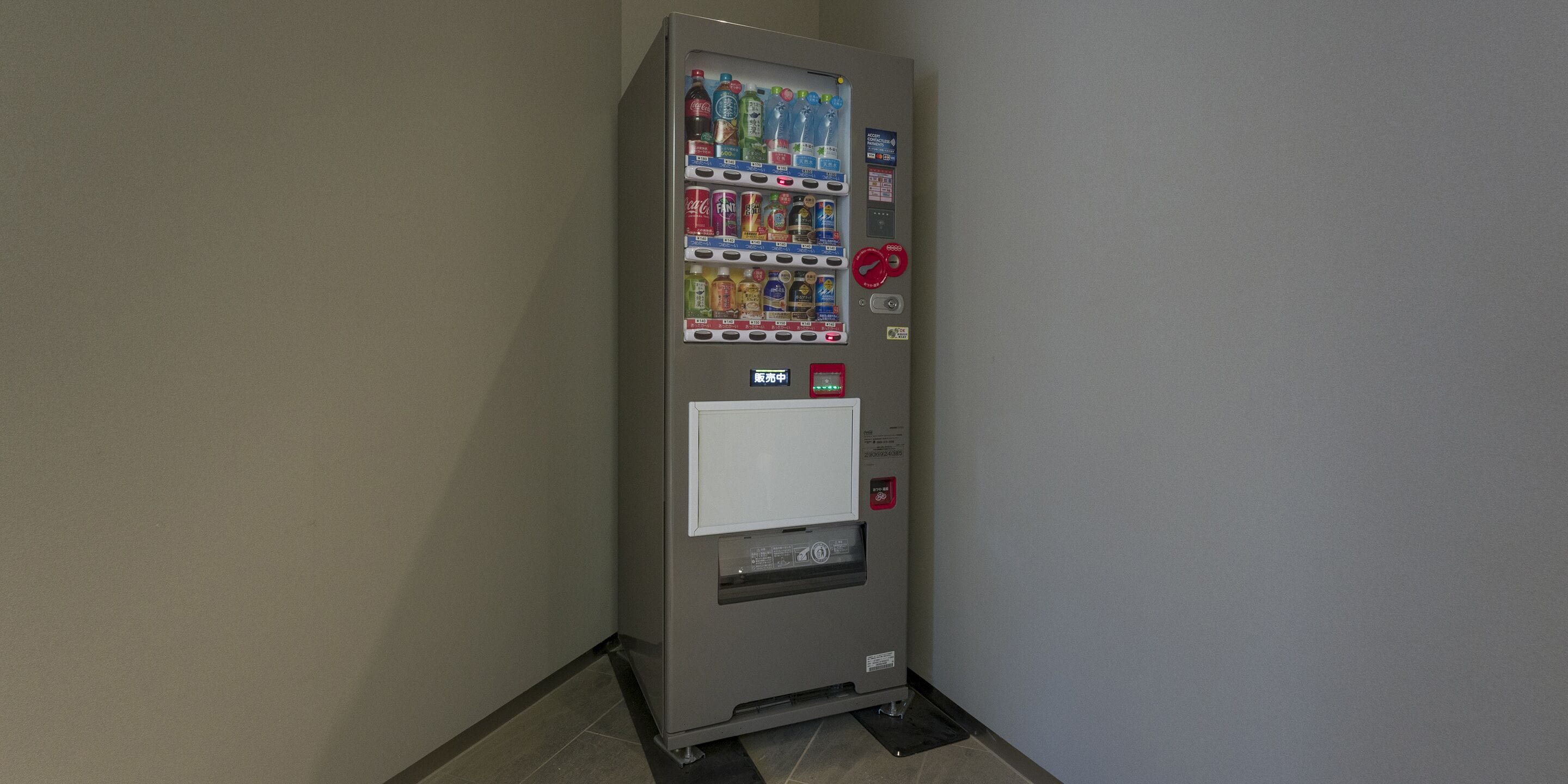 Máquina expendedora con diversas bebidas y aperitivos, una ranura para pagos y una ranura para devolución de monedas.