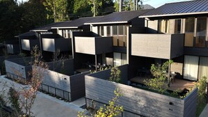 A modern residential building with multiple levels, large windows, and a rooftop terrace.