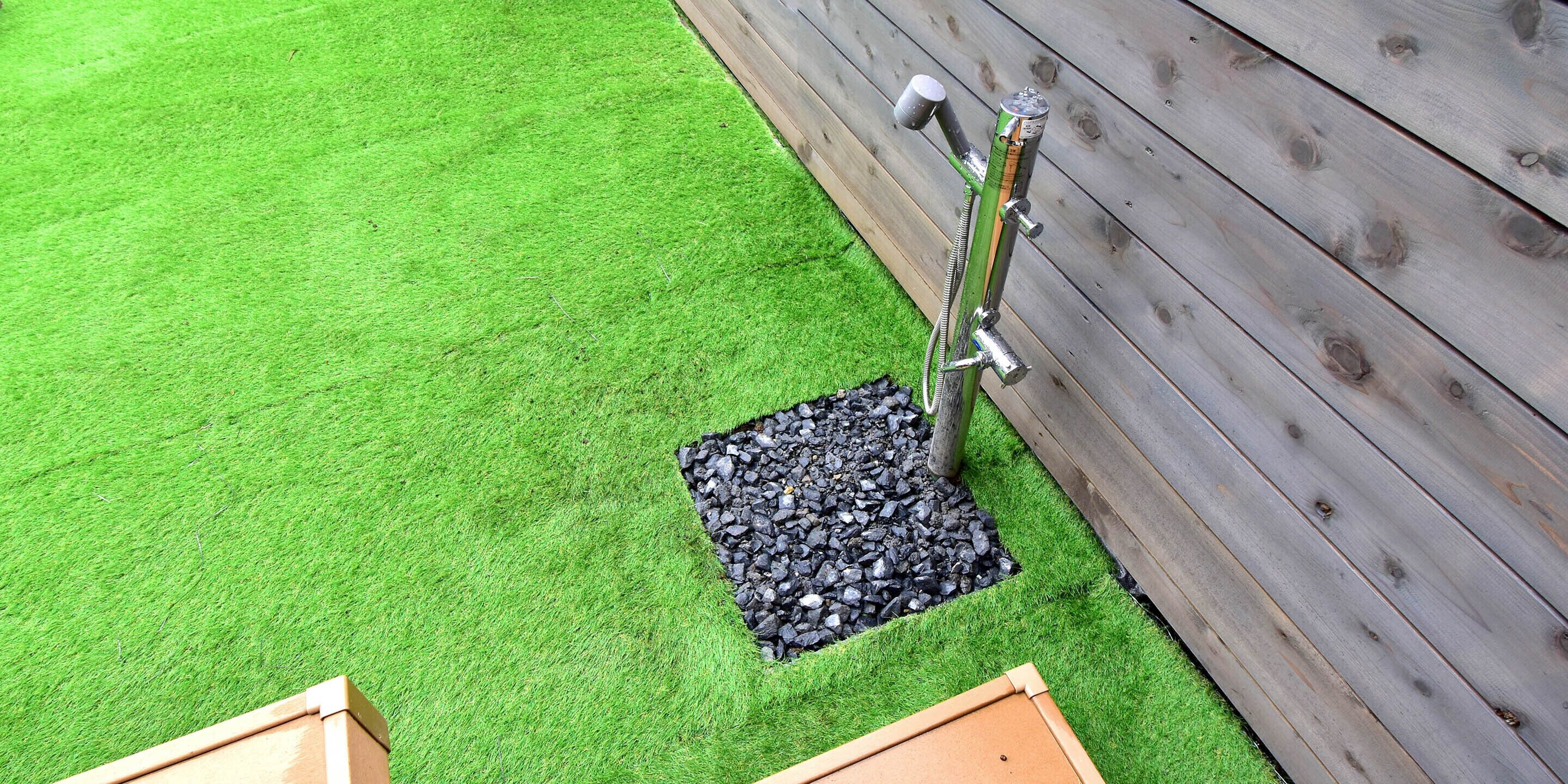 Een stuk kunstgras met een houten omheining en een metalen constructie.