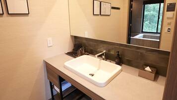 A modern bathroom with a large sink, a mirror, and a window.