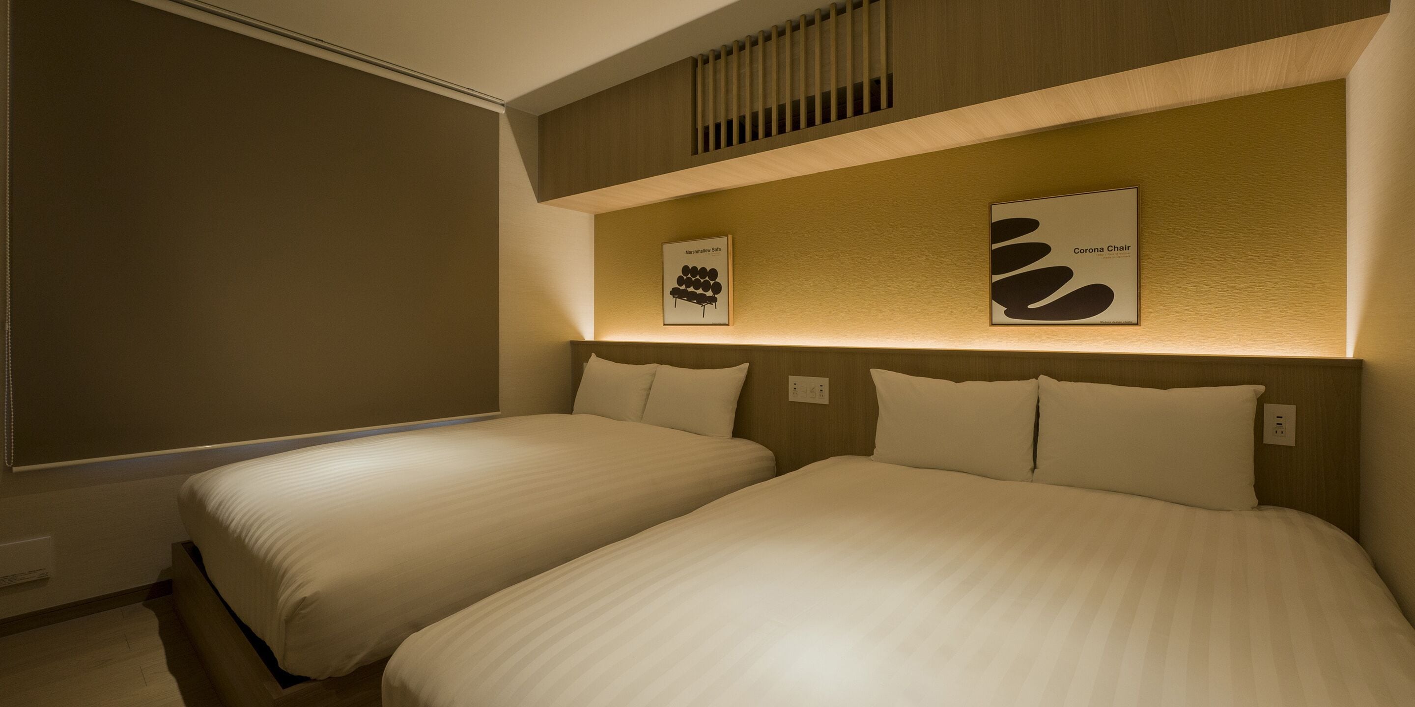 A hotel room with two beds, a wooden headboard, and two framed pictures on the wall.