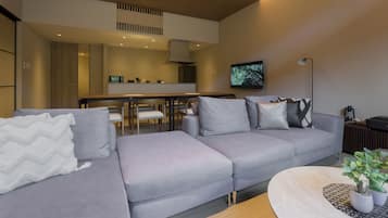 Un salon moderne avec un canapé gris, une table basse et un téléviseur fixé au mur.