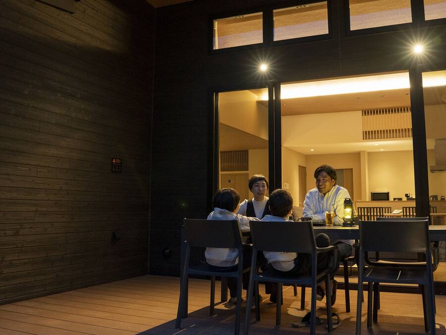 A group of people seated at a table in a modern, well-lit dining area with a wooden floor and large windows.
