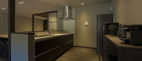 A modern kitchen with a built-in oven, a coffee machine, and a refrigerator.
