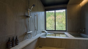 A modern bathroom with a bathtub, shower, and large window.
