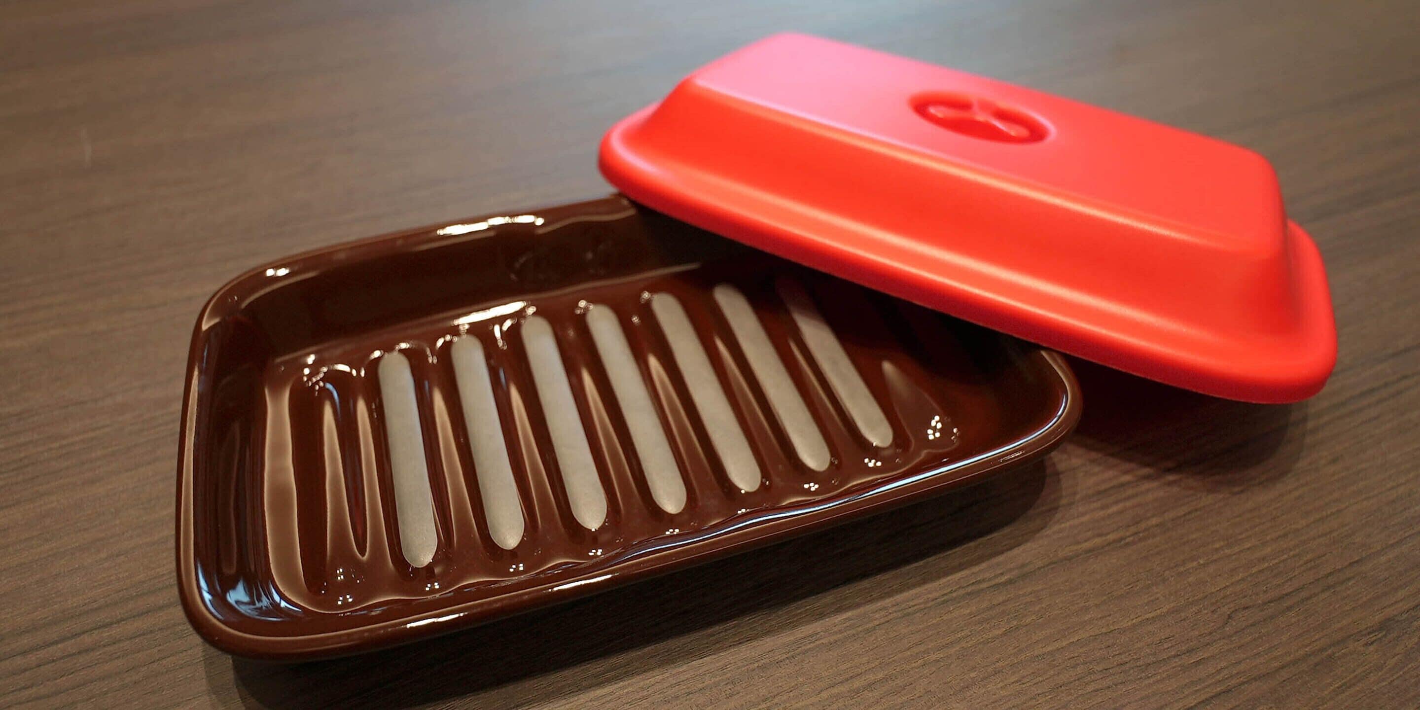 A brown rectangular object with a red lid on a wooden surface.