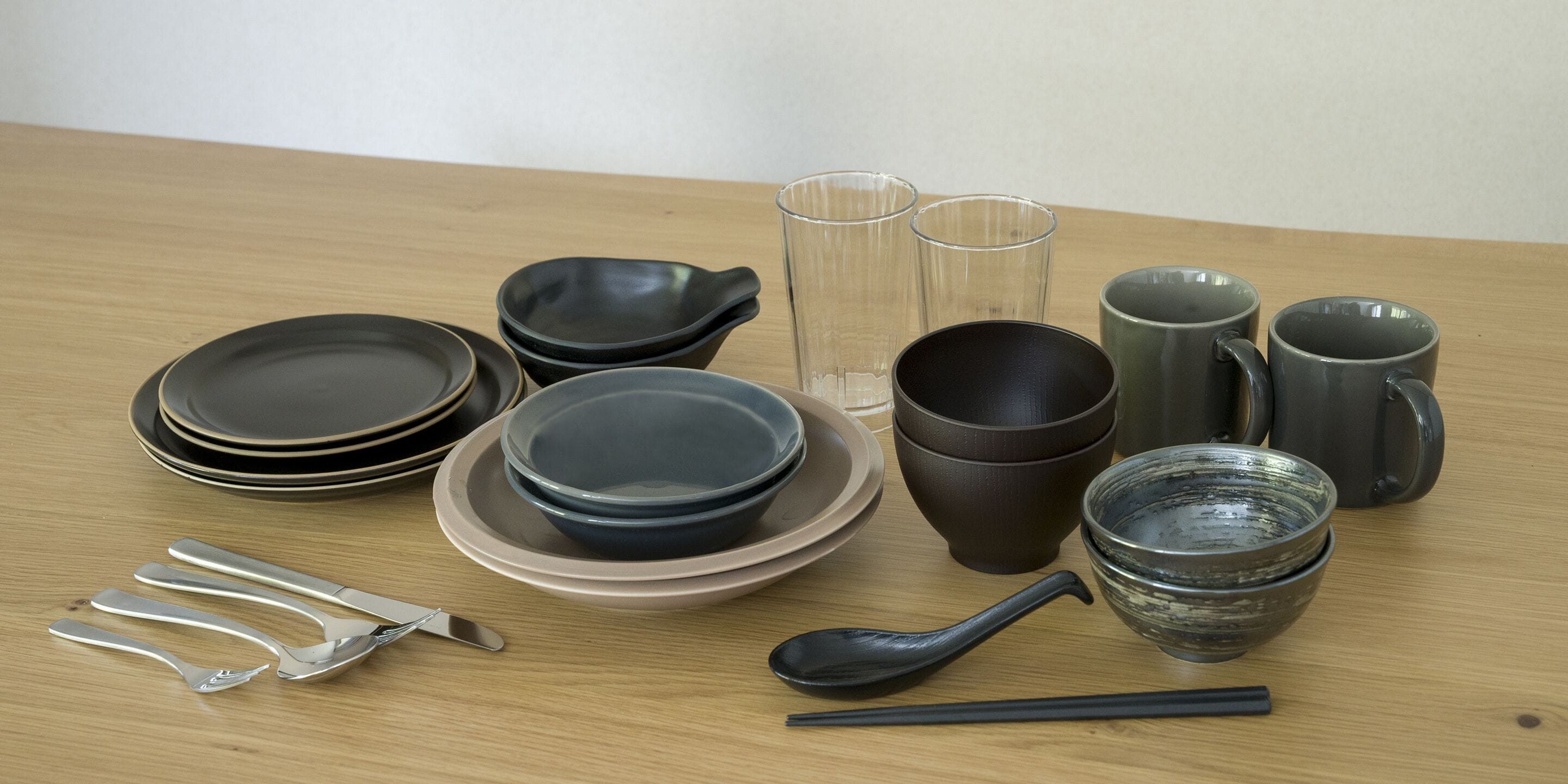 Une table avec différents plats, tasses et ustensiles.