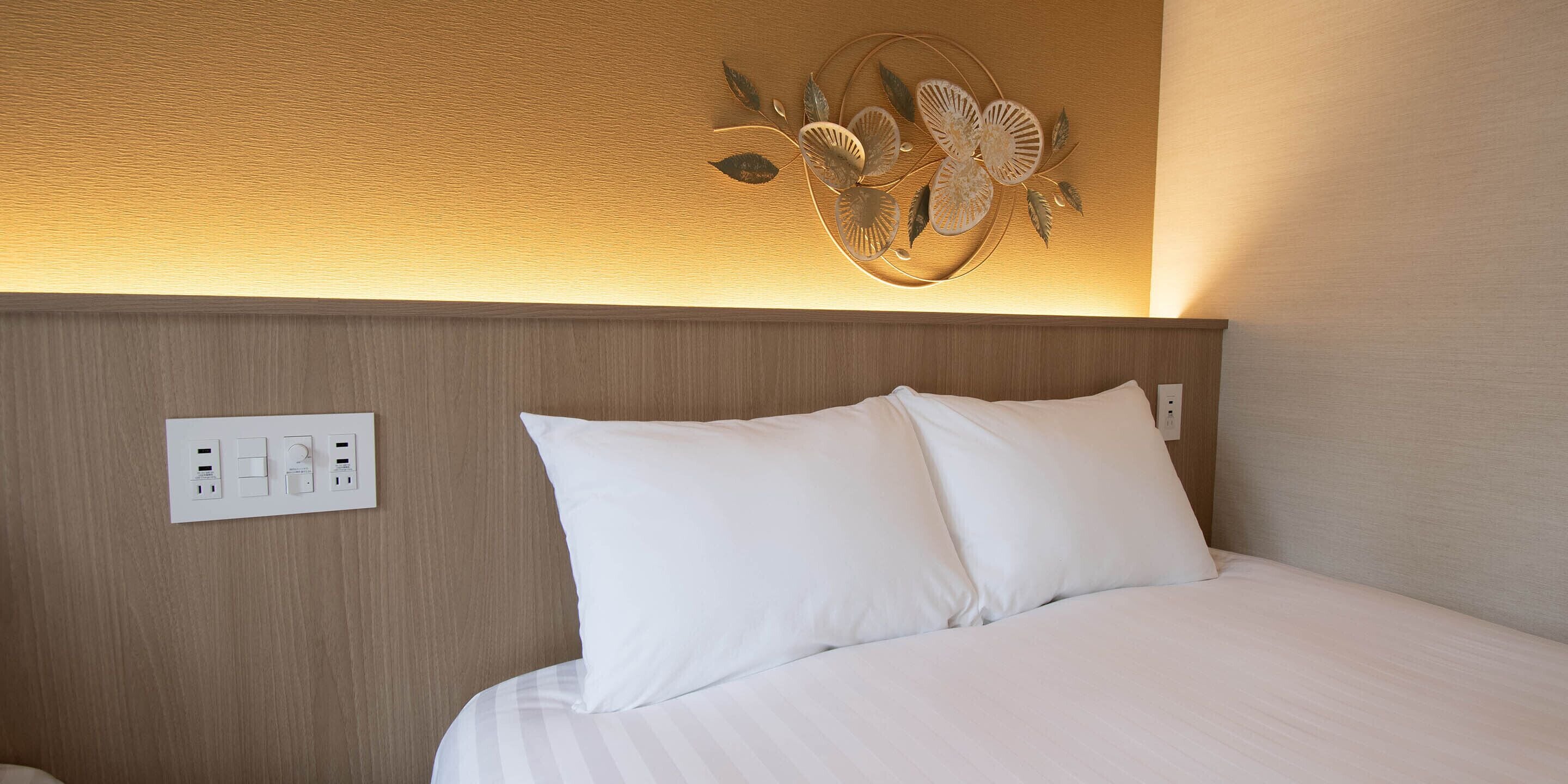 Habitación de hotel con una cama, un enchufe en la pared y un adorno mural.