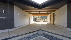 A modern building entrance with a concrete floor, wooden beams, and a chain-link fence.
