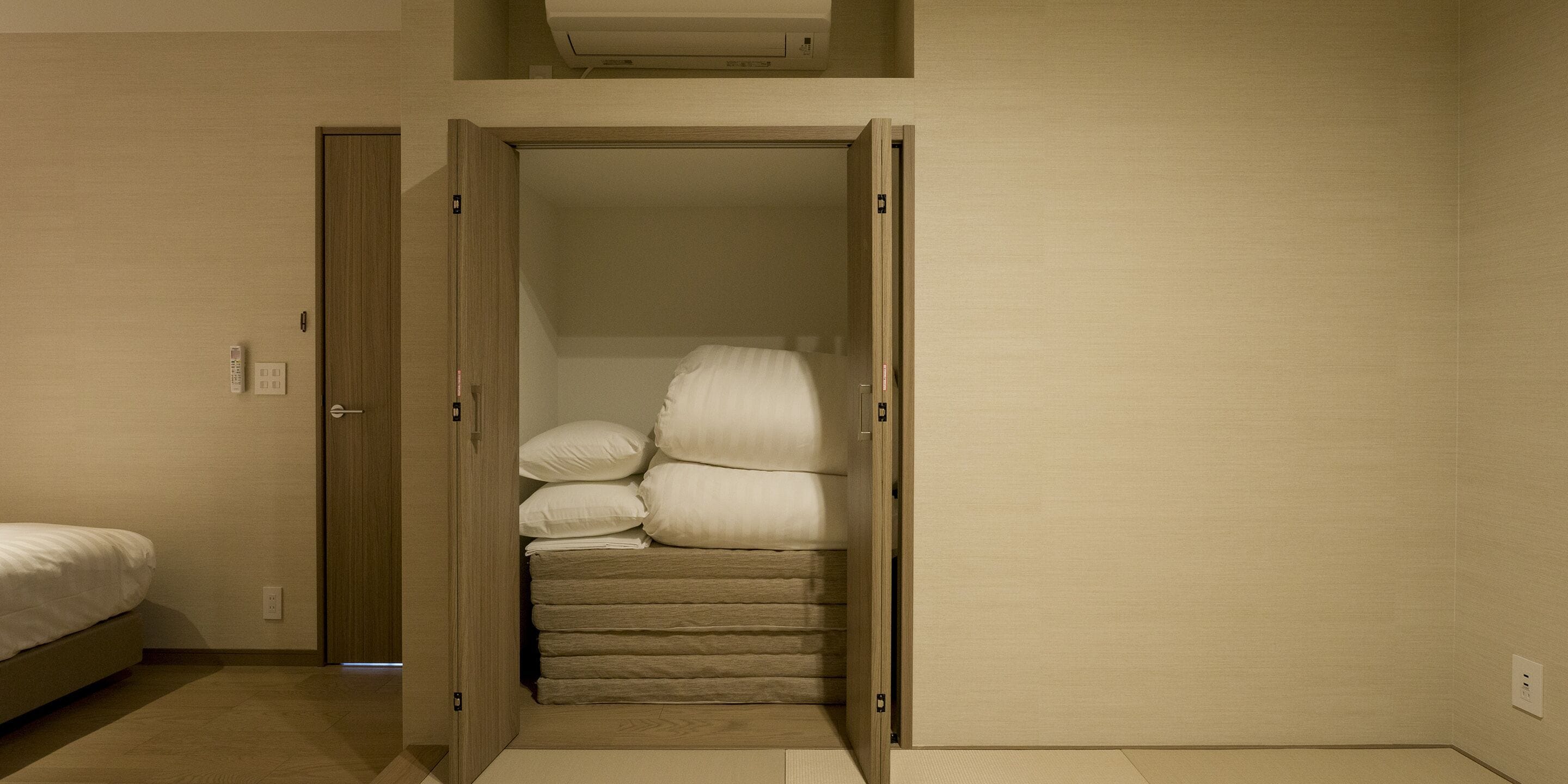 Ein Schlafzimmer mit einem Bett, einem Kleiderschrank mit Spiegel und einem kleinen Fenster.
