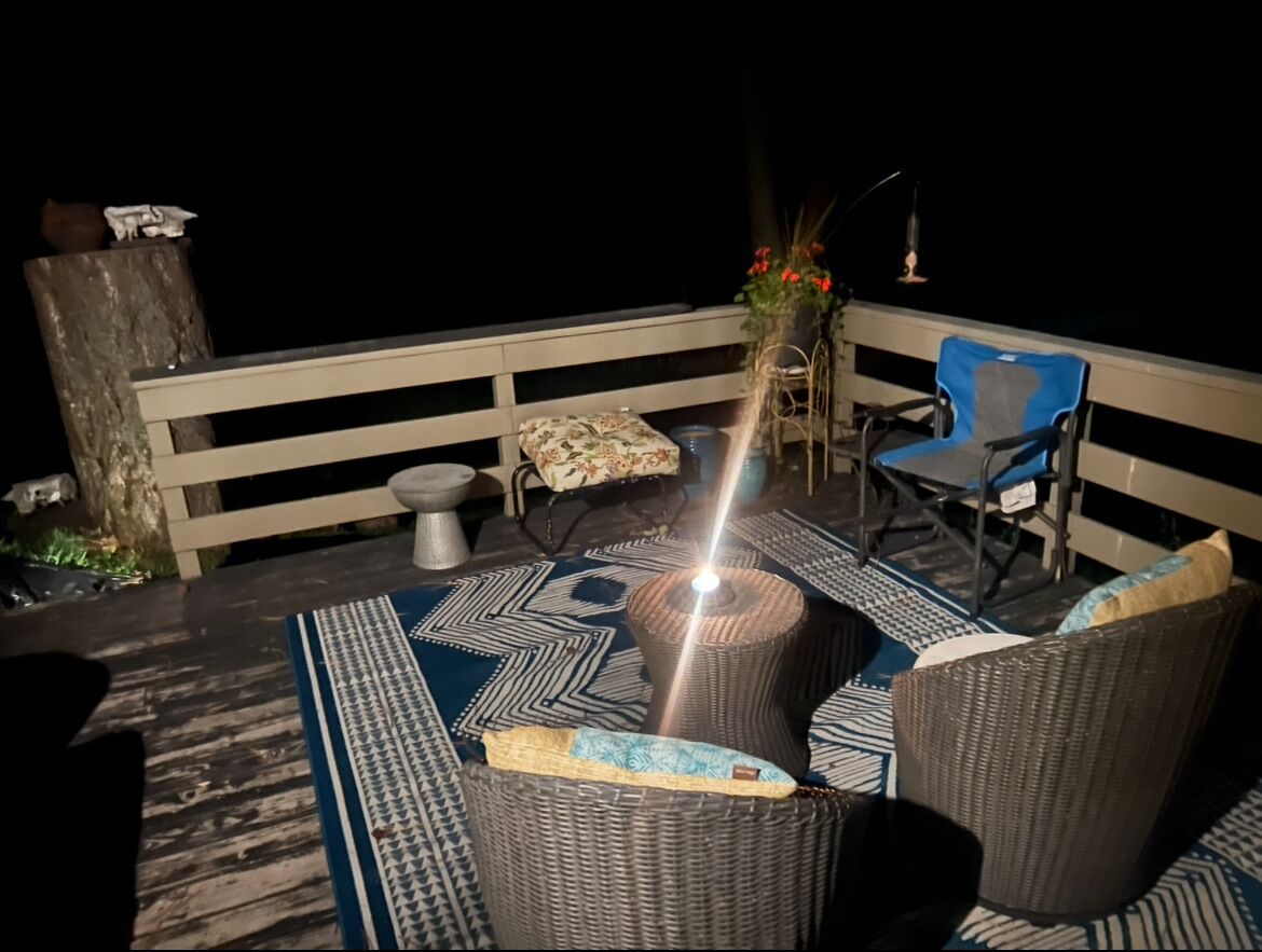 A balcony with wicker furniture, a blue chair, and a potted plant.