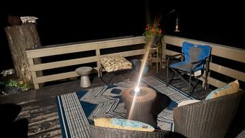 A balcony with wicker furniture, a blue chair, and a potted plant.