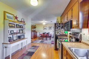 A kitchen with wooden cabinets, a refrigerator, and a dining area with a table and chairs.