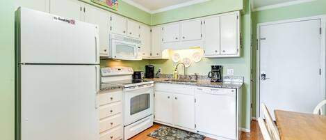 A compact kitchen with white appliances, a microwave, a stove, and a coffee maker.