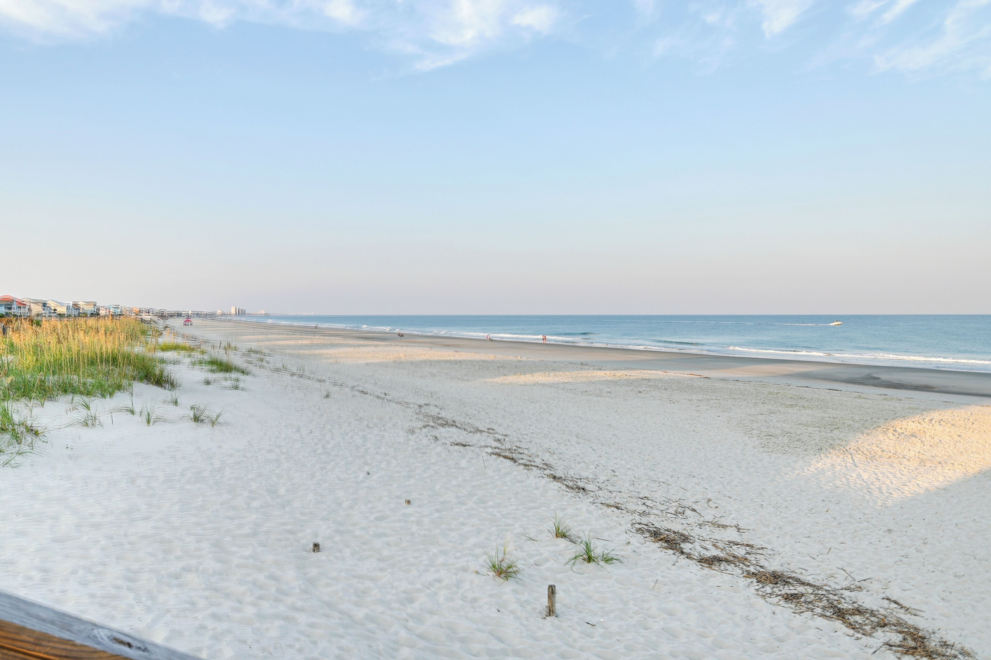 Een strand met een houten promenade en gebouwen op de achtergrond.
