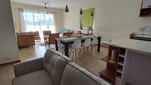 Un salon moderne comprenant un canapé, une table à manger et des chaises. On y trouve également un coin cuisine avec un plan de travail et des placards.