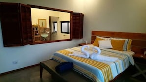 Une chambre d’hôtel avec un lit, un banc, un miroir et une petite table.