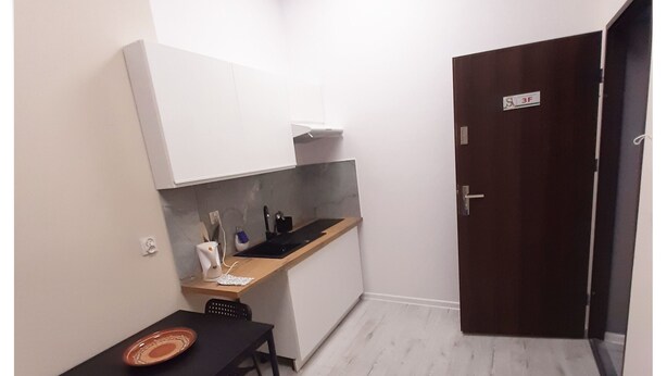 A compact kitchen with a dining table, a single chair, and a small countertop.