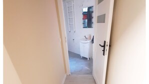 A narrow hallway with a white door leading to a bathroom.