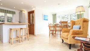 A spacious living area with a kitchen, wooden furniture, and a dining table. - The Old Barn (Penzance)
