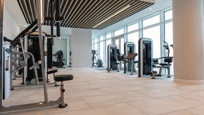 Une salle de sport moderne équipée de divers appareils d’exercice, dotée de grandes fenêtres et d’un plafond à rayures.
