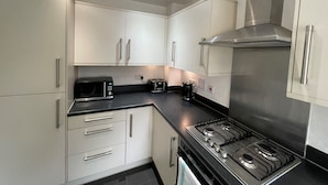 Een moderne keuken met witte kastjes, een roestvrijstalen fornuis en een magnetron.