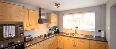 A modern kitchen with wooden cabinets, stainless steel appliances, and a large window providing natural light.