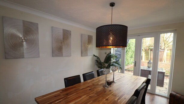 A dining area with a wooden table, black chairs, and a hanging light fixture. - Binfield: Spacious Spectacular Five Bedroom House (Binfield)