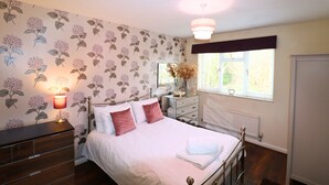 A bedroom with a bed, dresser, vanity, and a window with blinds. - Binfield: Spacious Spectacular Five Bedroom House (Binfield)