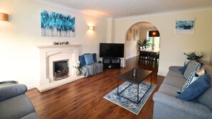A living room with a fireplace, a flat-screen TV, a sofa, and a coffee table. - Binfield: Spacious Spectacular Five Bedroom House (Binfield)