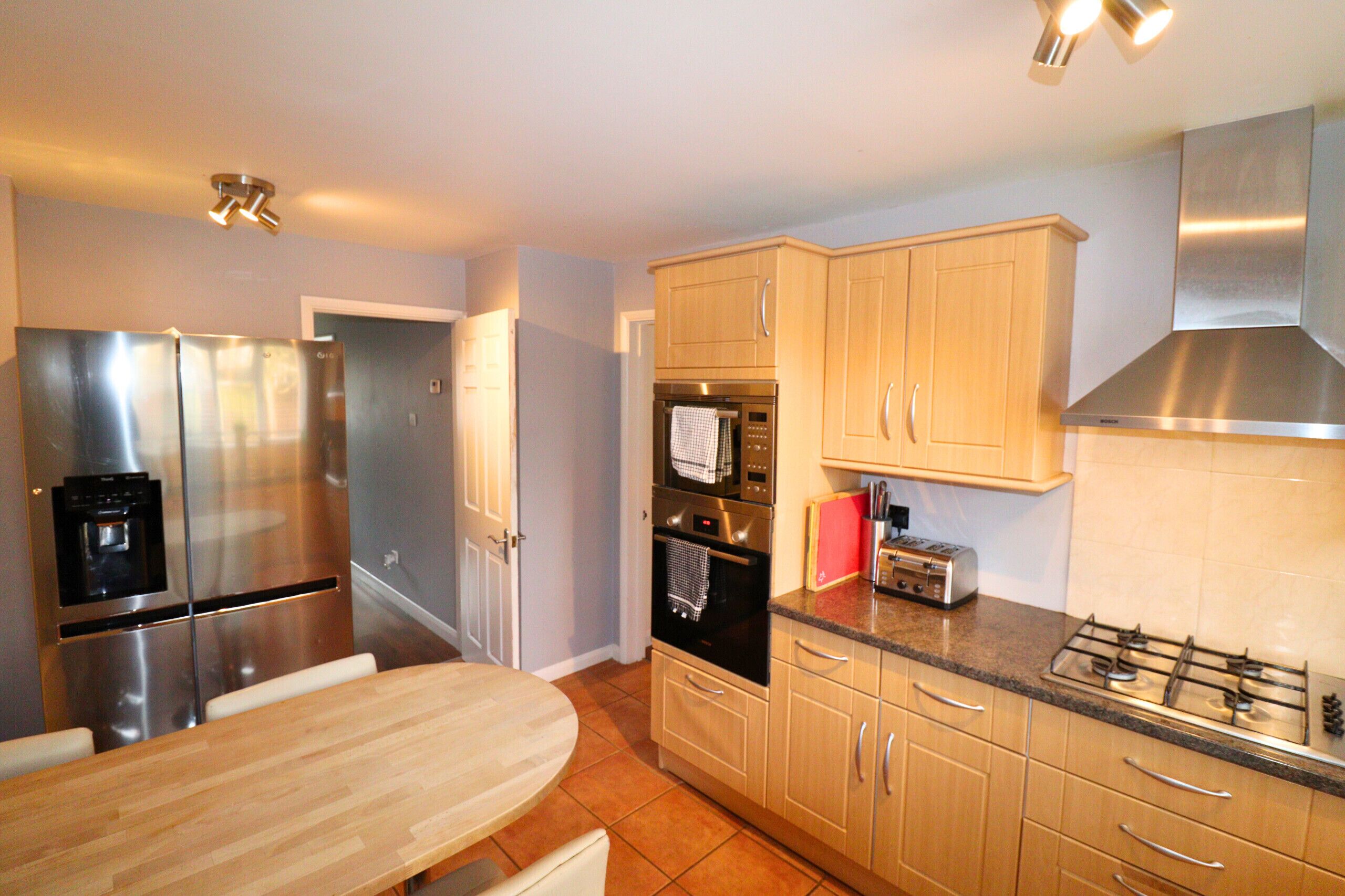 A modern kitchen with stainless steel appliances, wooden cabinets, and a granite countertop.